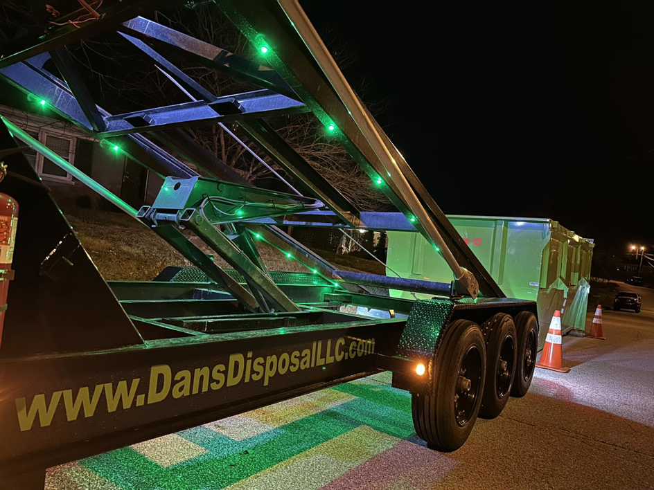 A Dan's Disposal LLC dumpster trailer with green lights at night, ready for service in Richmond, KY.