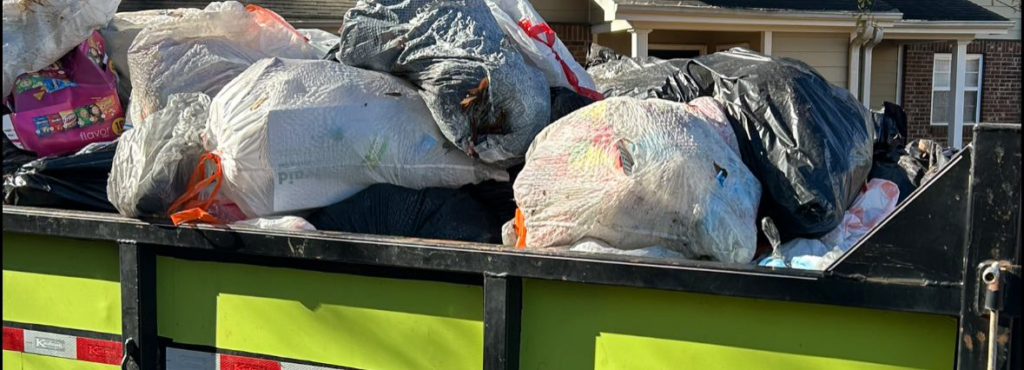 A large dumpster or truck bed overflowing with trash bags and various junk items, collected by 247 Junk Removal Greenville SC in Greenville, SC.