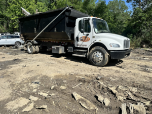 A Dts dumpster rentals truck with a black dumpster container parked on a muddy job site in Memphis, TN.