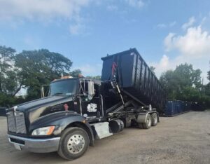 A Long Dumpster Rentals truck unloading a large black dumpster, ready for general junk removal service in Rochester, NY.
