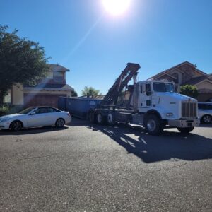 A Tidy up time dumpster truck with a blue roll-off container parked on a residential street in El Paso, TX.