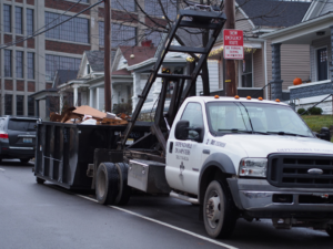 A Dependable Dumpsters truck with a full dumpster of debris on a residential street in Louisville, KY.