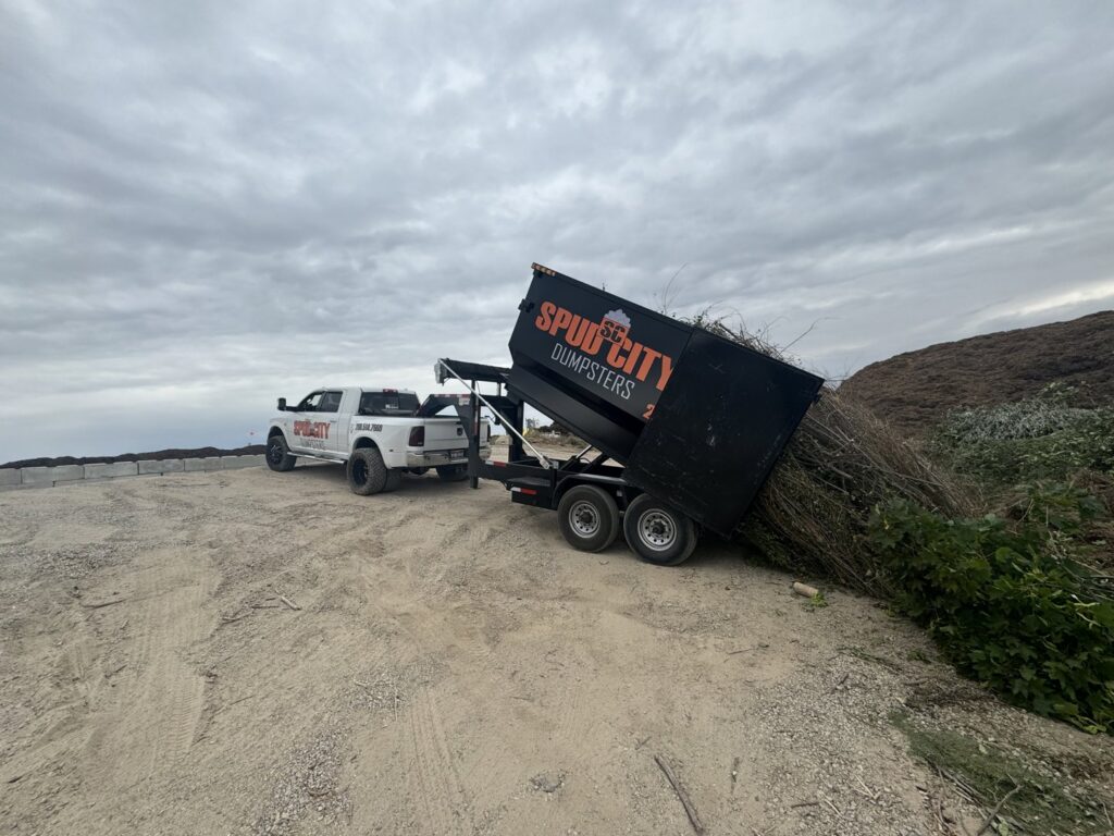 A SpudCity Dumpsters truck unloading green waste from a dumpster trailer at a disposal site in Caldwell, ID.