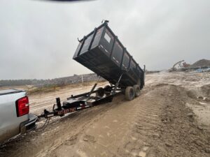 A dumpster trailer unloading a load of junk and debris at a muddy landfill for Trash N Go Dumpster's in Orlando, FL.