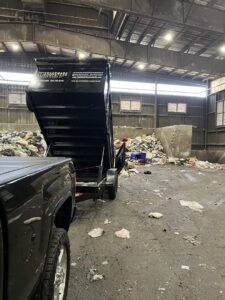 A Trademark Dumpsters trailer unloading a full load of trash at a disposal facility, completing a junk removal job in Wilmington, DE.