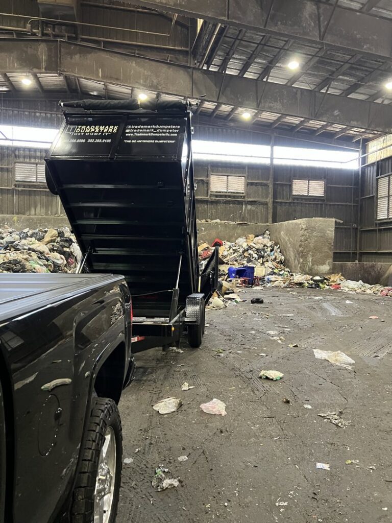 A Trademark Dumpsters trailer unloading a full load of trash at a disposal facility, completing a junk removal job in Wilmington, DE.