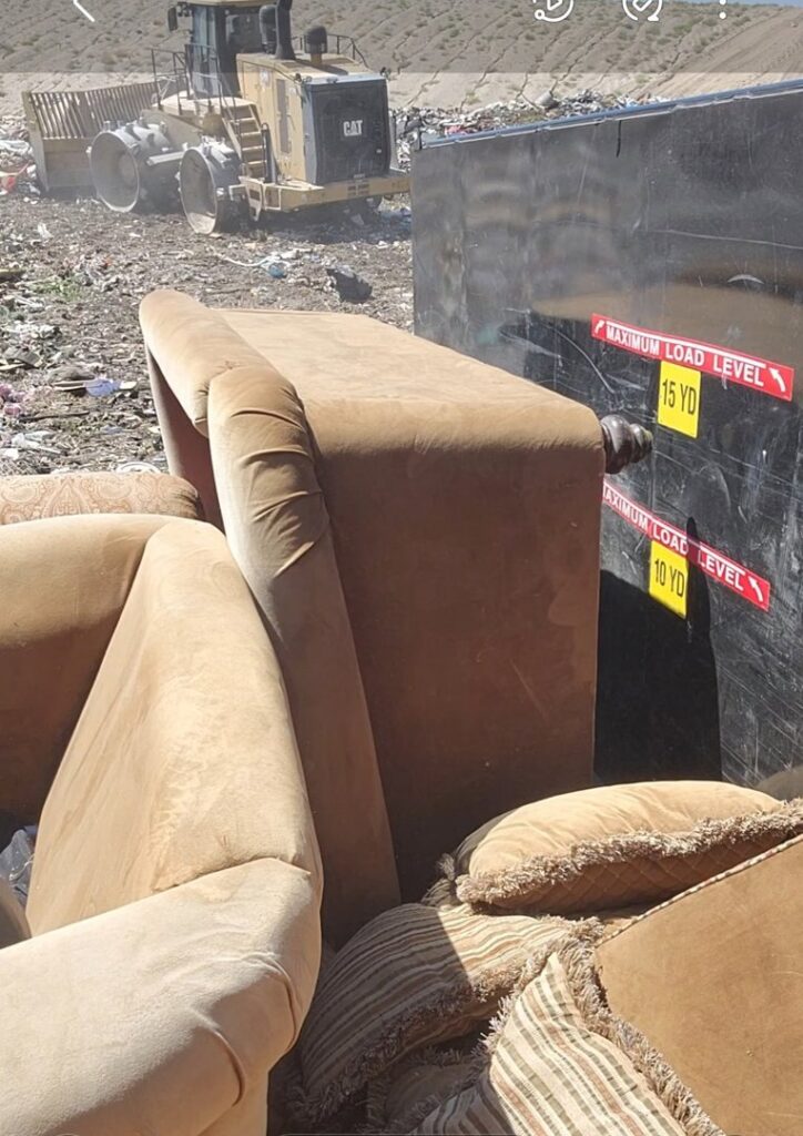 A dumpster containing a couch and other junk at a landfill, demonstrating services by Jigsaw Transport and Waste in Albuquerque, NM.