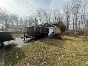 A Trademark Dumpsters roll-off trailer with a pile of junk next to it, ready for removal at a residential property in Wilmington, DE.