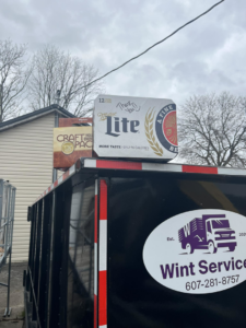 A black dumpster from Wint Services, LLC, filled with junk and debris, ready for removal in Colorado Springs, CO.