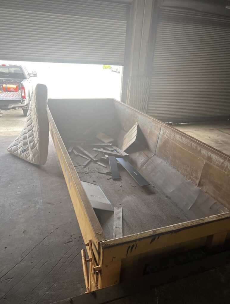 A large dumpster containing a mattress and various debris, provided by Junk Be Gone in Miami, FL.