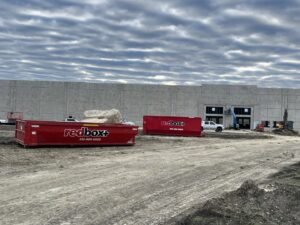 Two redbox+ dumpsters at a large construction site for debris removal by redbox+ Dumpsters of Greater Austin in Austin, TX