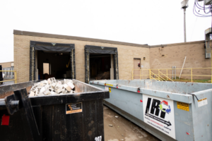 Two large dumpsters, one filled with construction debris, provided by Logistics Recycling Inc. outside a building in Green Bay, WI.