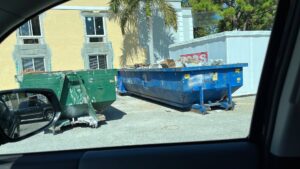 Two dumpsters filled with construction debris and general junk outside a building, provided by Coast to Coast Disposal in Orlando, FL.