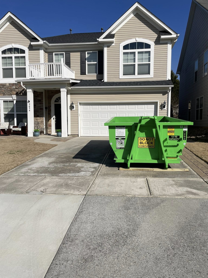A green DumpStor dumpster placed on a residential driveway, ready for junk removal projects in Charlotte, NC.