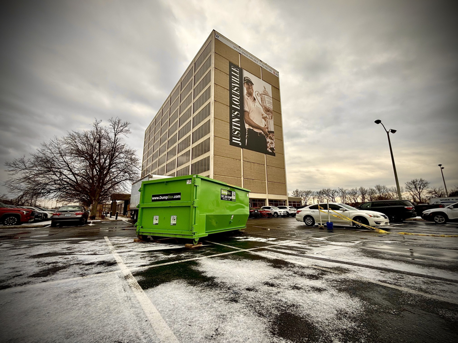 A green DumpStor of Louisville roll-off dumpster placed in a commercial parking lot for a junk removal project in Louisville, KY.