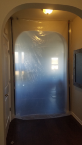 A clear plastic dust containment barrier set up in a doorway for a handyman job by Emergency Response Team Nashville, TN