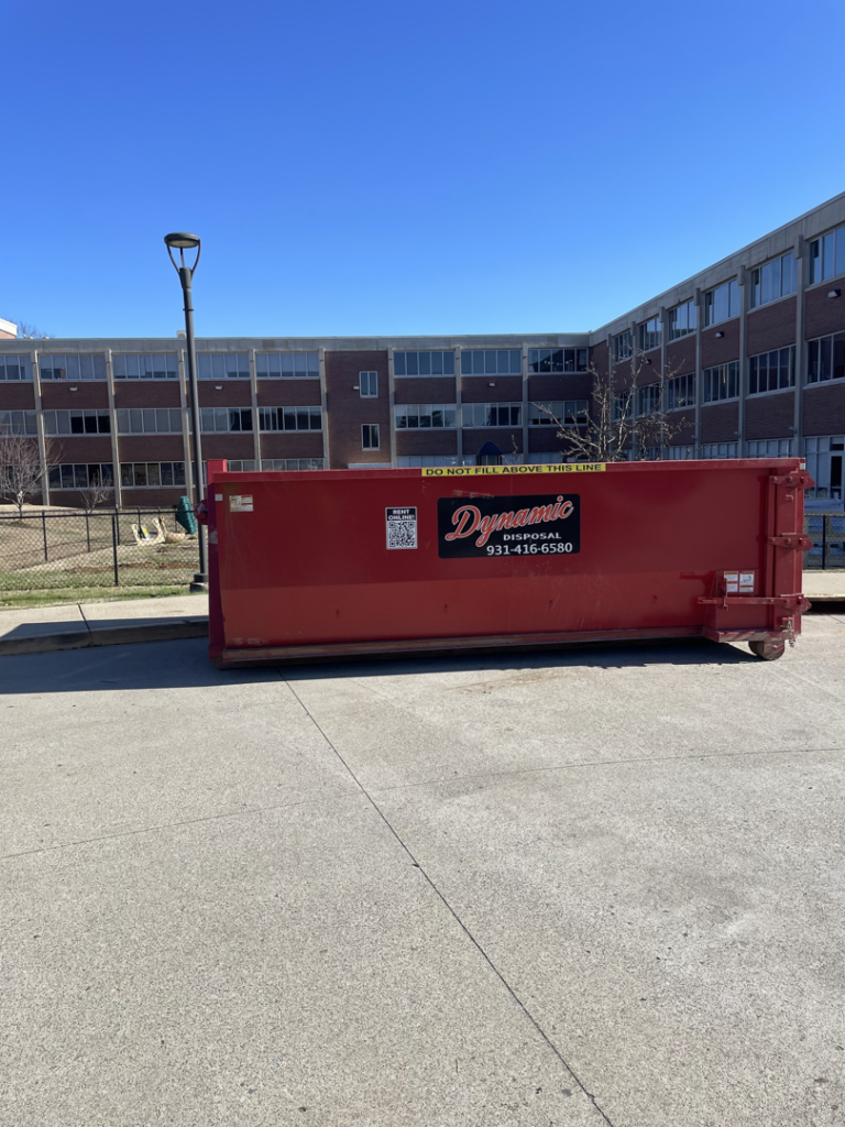 A large red roll-off dumpster from Dynamic Disposal placed on a paved area in Franklin, TN.