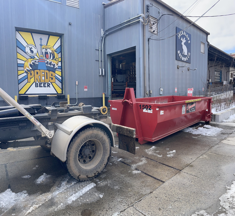 A Dynamic Disposal truck placing a roll-off dumpster at a commercial site in Franklin, TN.