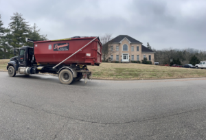 A Dynamic Disposal truck delivering a roll-off dumpster to a residential property in Franklin, TN.