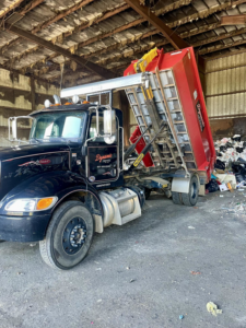 A Dynamic Disposal truck unloading a roll-off dumpster filled with junk at a disposal site in Franklin, TN.