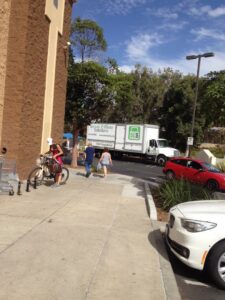 A sign detailing pricing for e-waste collection at an outdoor event by SES Secure E-Waste Solutions Inc. in San Diego, CA.