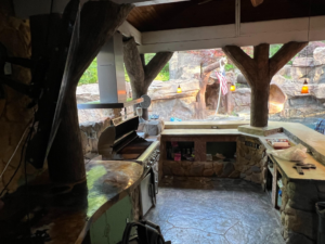An elaborate outdoor kitchen and living area with custom stone work, grill, and range hood by Burton Restoration LLC in Bend, OR.