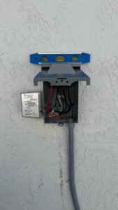 Exterior electrical box installation in progress with a level, part of a project by Belair Inc. in Saint Cloud, FL