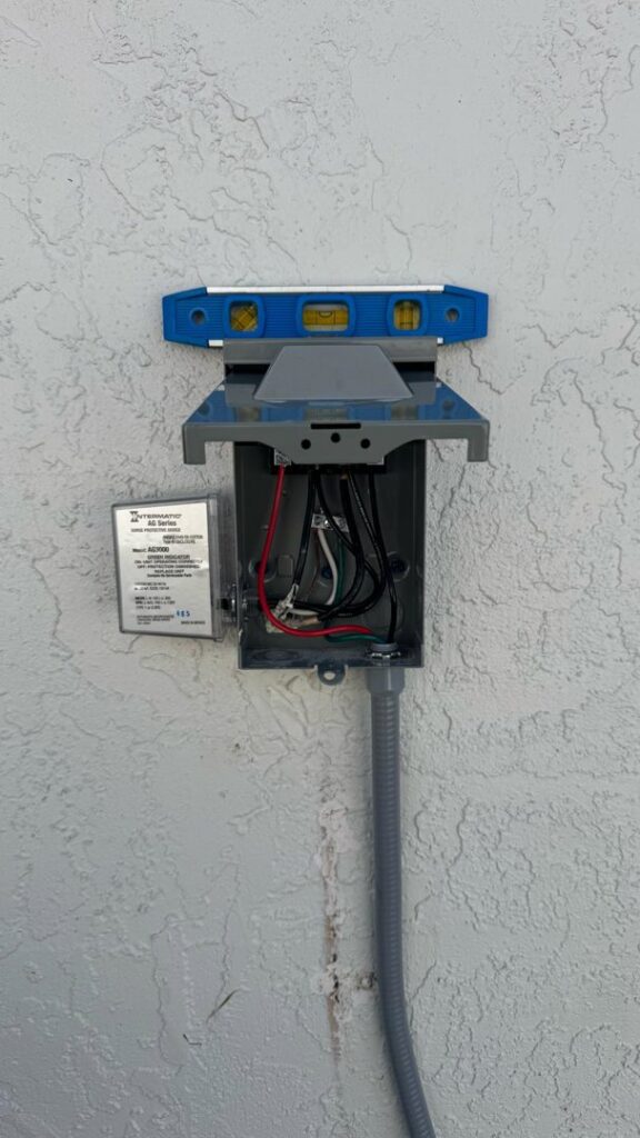 Exterior electrical box installation in progress with a level, part of a project by Belair Inc. in Saint Cloud, FL