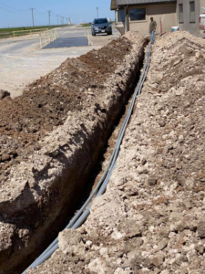 Electrical conduits being laid in a trench by Harvey's Electric in Perryton, TX