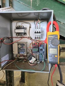 A close-up of an electrical control panel undergoing diagnostic testing with a multimeter by Denali Electric LLC in San Antonio, TX