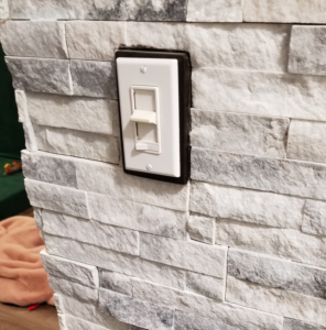 A newly installed electrical light switch on a stone veneer wall by Quality Home Improvement in Pulaski, Chicago, IL.
