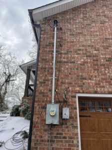An electrical meter and conduit installation on the side of a brick house by HHS Contractors in Providence Village, TX.
