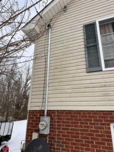 An electrical meter and conduit installation on the side of a house with siding by HHS Contractors in Providence Village, TX.
