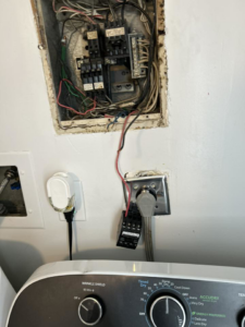 Exposed electrical panel wiring and a washing machine hookup, showing electrical services by Katzenstein llc handyman in Council Bluffs, IA.