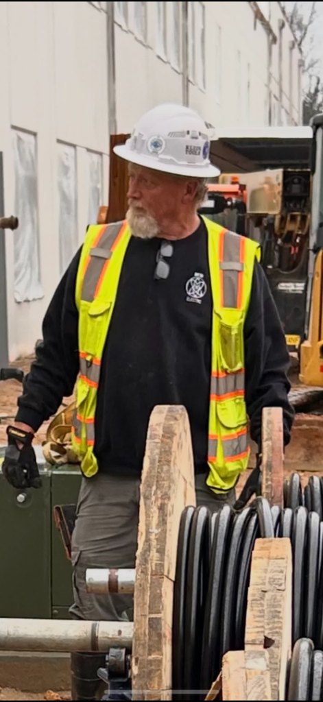 An electrician in a hard hat and safety vest on a job site for Reid Electric in Denton, TX
