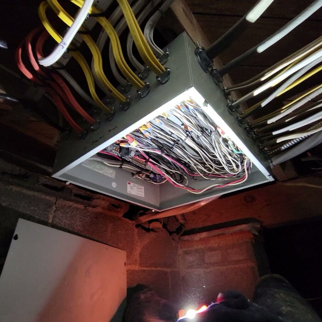 A MorLite Electric handyman working on complex electrical wiring inside an open junction box in Newport News, VA.