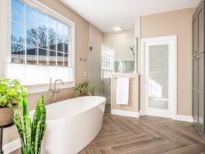 An elegant bathroom remodel with a freestanding tub, large window, and walk-in shower by Desert Remodel in Scottsdale, AZ.