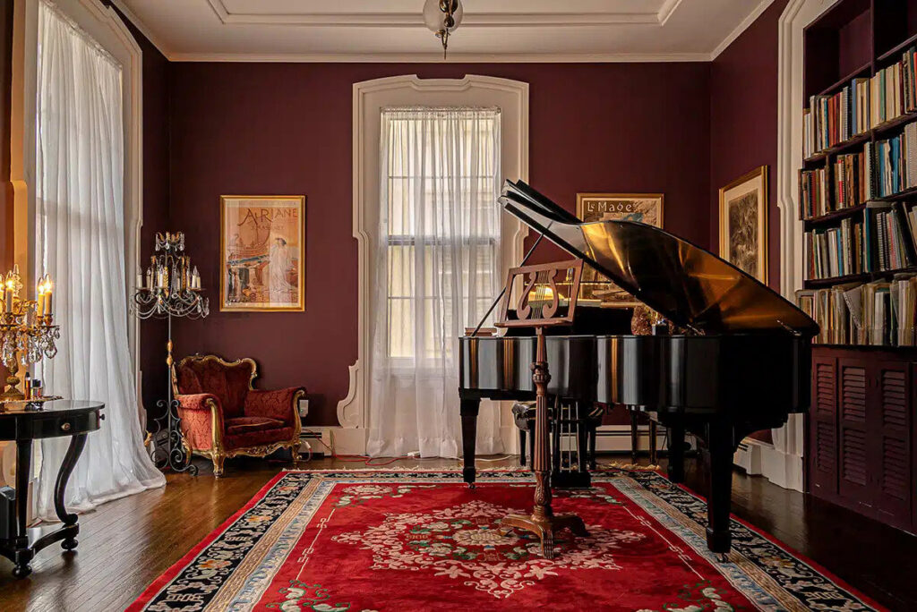 An elegantly painted interior room with dark red walls and a grand piano, showcasing work by GO Painting in New Haven, CT