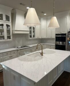An elegant kitchen showcasing white cabinets, a large island with a sink, and beautiful marble-look countertops by Javier's Countertops in Springdale, AR