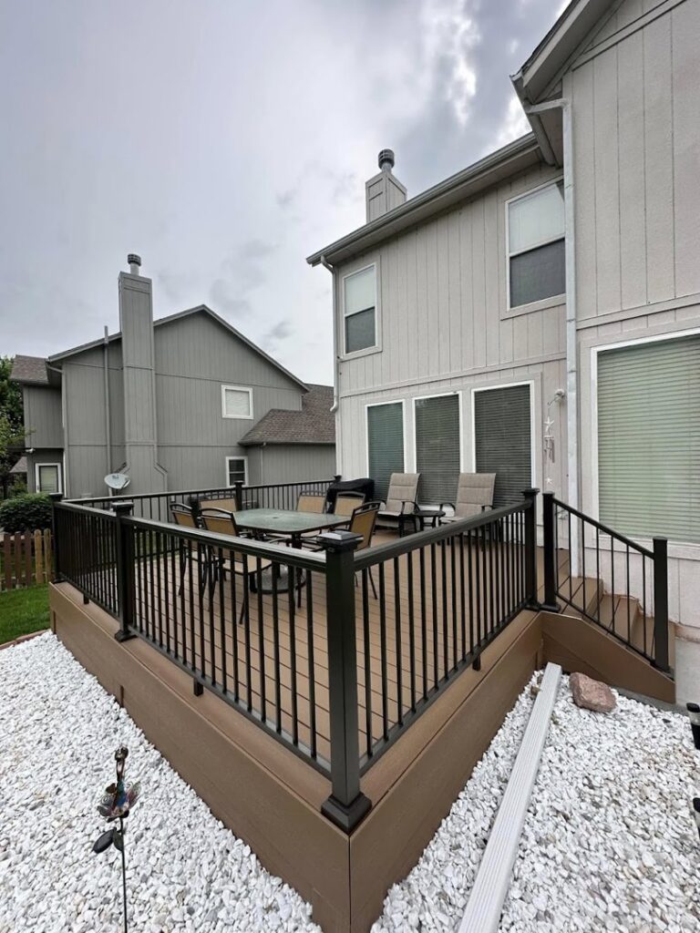 An elevated deck with sleek black railings and white decorative stones below, completed by Deckscape KC in Kansas City, MO.