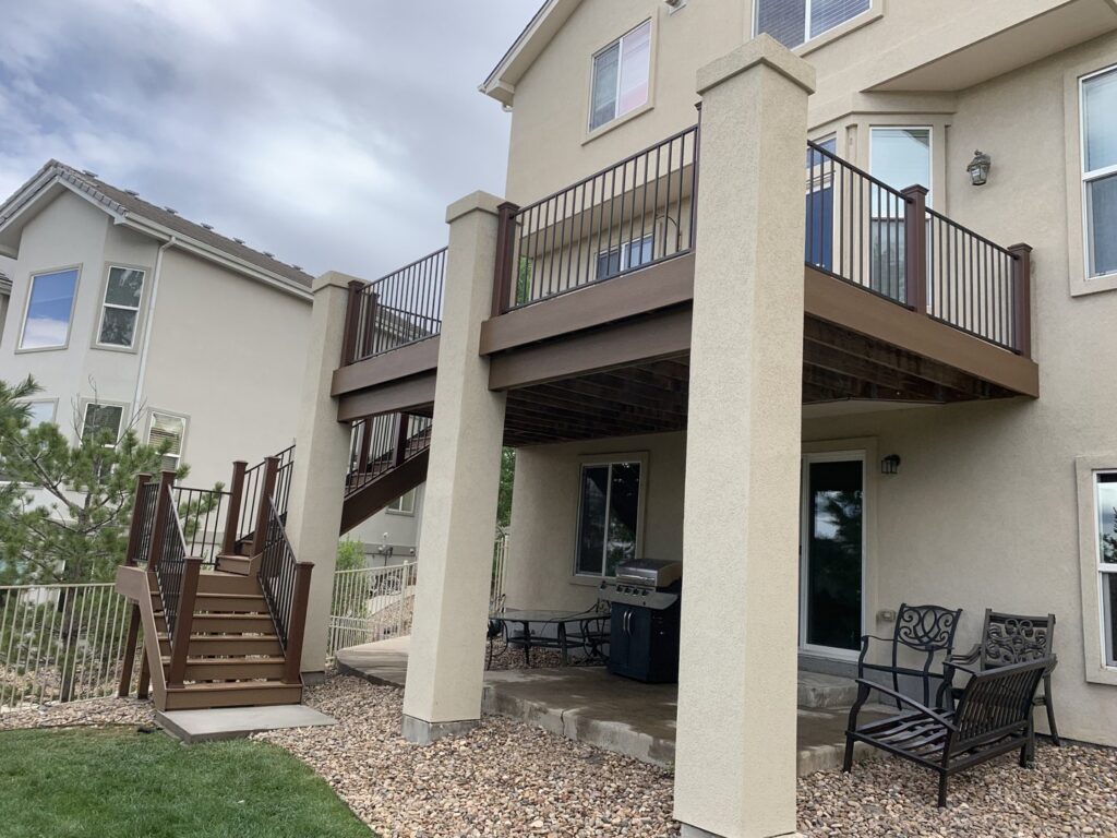 An elevated deck with sturdy columns, stairs, and railings, built by Lnk Deck & Remodels, LLC in Aurora, CO.