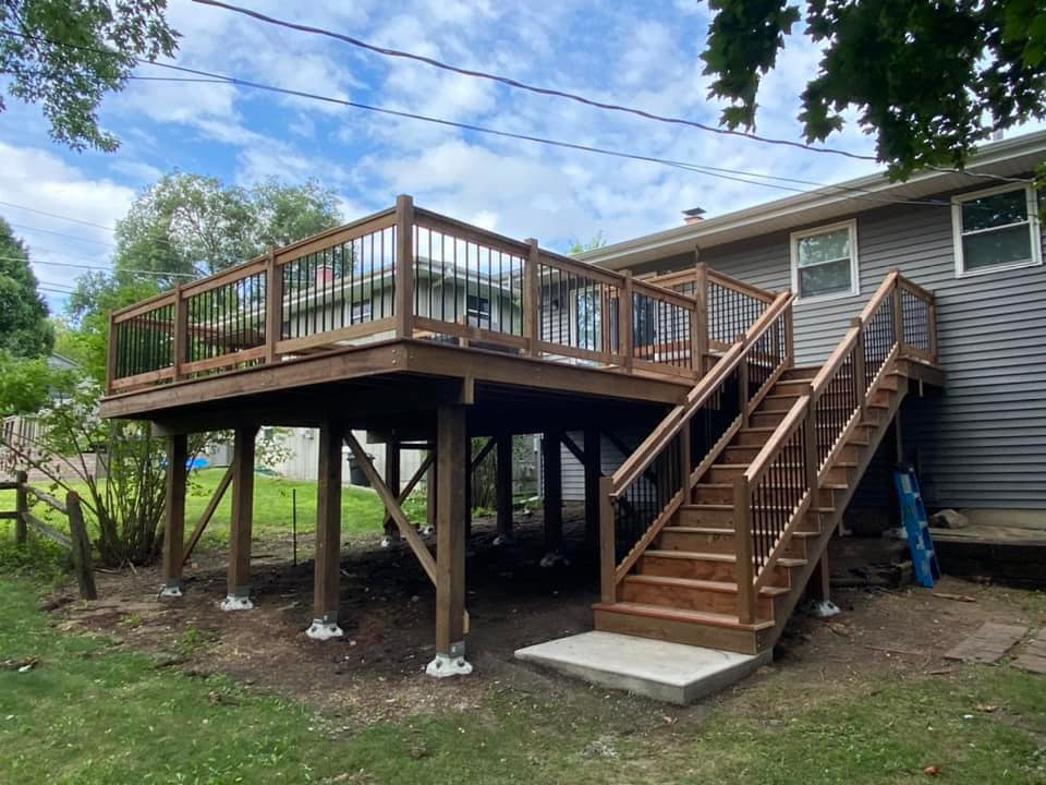 An elevated wooden deck with stairs and black balusters, expertly built by Strom Contracting LLC in Crystal Lake, IL.