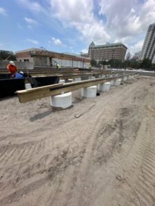 Construction site showing elevated wooden beams resting on concrete piers, indicating foundation work by Bayside Concrete & Construction in Tampa, FL