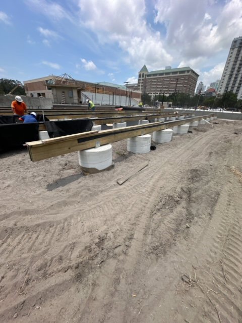 Construction site showing elevated wooden beams resting on concrete piers, indicating foundation work by Bayside Concrete & Construction in Tampa, FL