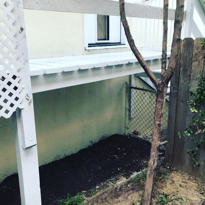 An elevated white wooden deck or patio cover built by EdkorCorp - Handyman Services in Long Beach, CA.