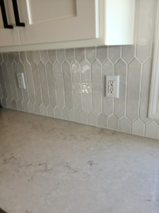 A stylish kitchen backsplash featuring light grey elongated hexagonal tiles installed by Bryan's Home Services in Fargo, ND.