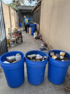 A Hazawaytoday.com employee collecting numerous paint cans and hazardous waste in an alleyway in El Segundo, CA