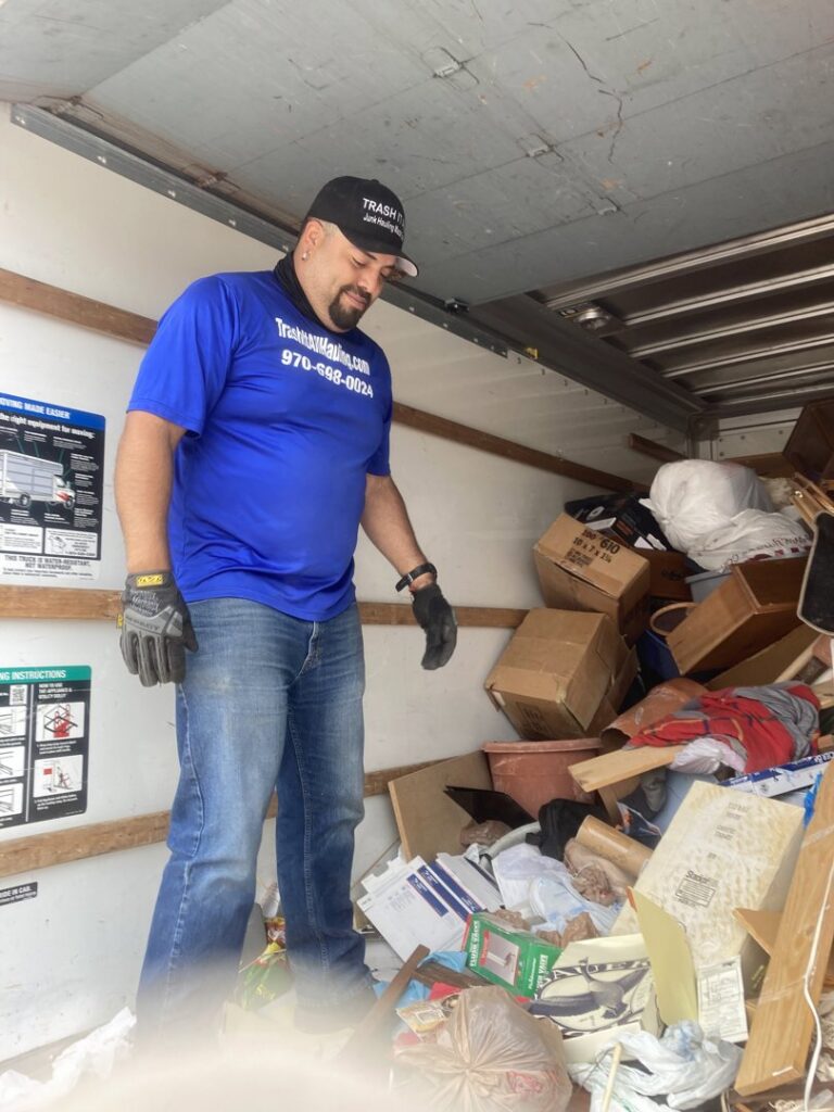 An employee standing inside a truck full of various junk items during a removal job by Trash It All Hauling And Junk Removal LLC in Fort Collins, CO.