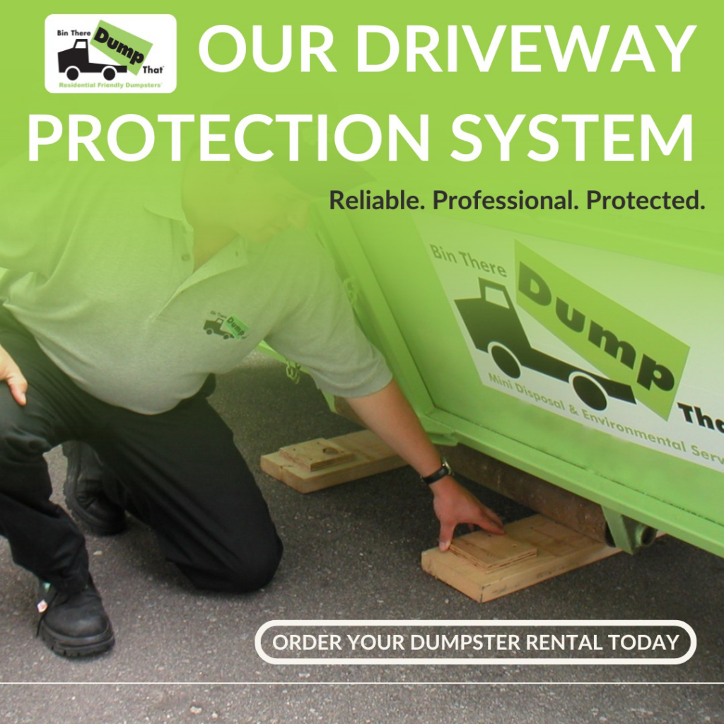 An employee installing driveway protection boards under a green dumpster from Bin There Dump That Chattanooga, TN.