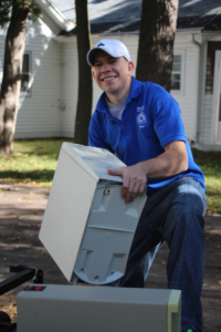An employee of New Earth Computer Recycling in Appleton, WI, loading a computer tower onto a trailer for recycling.